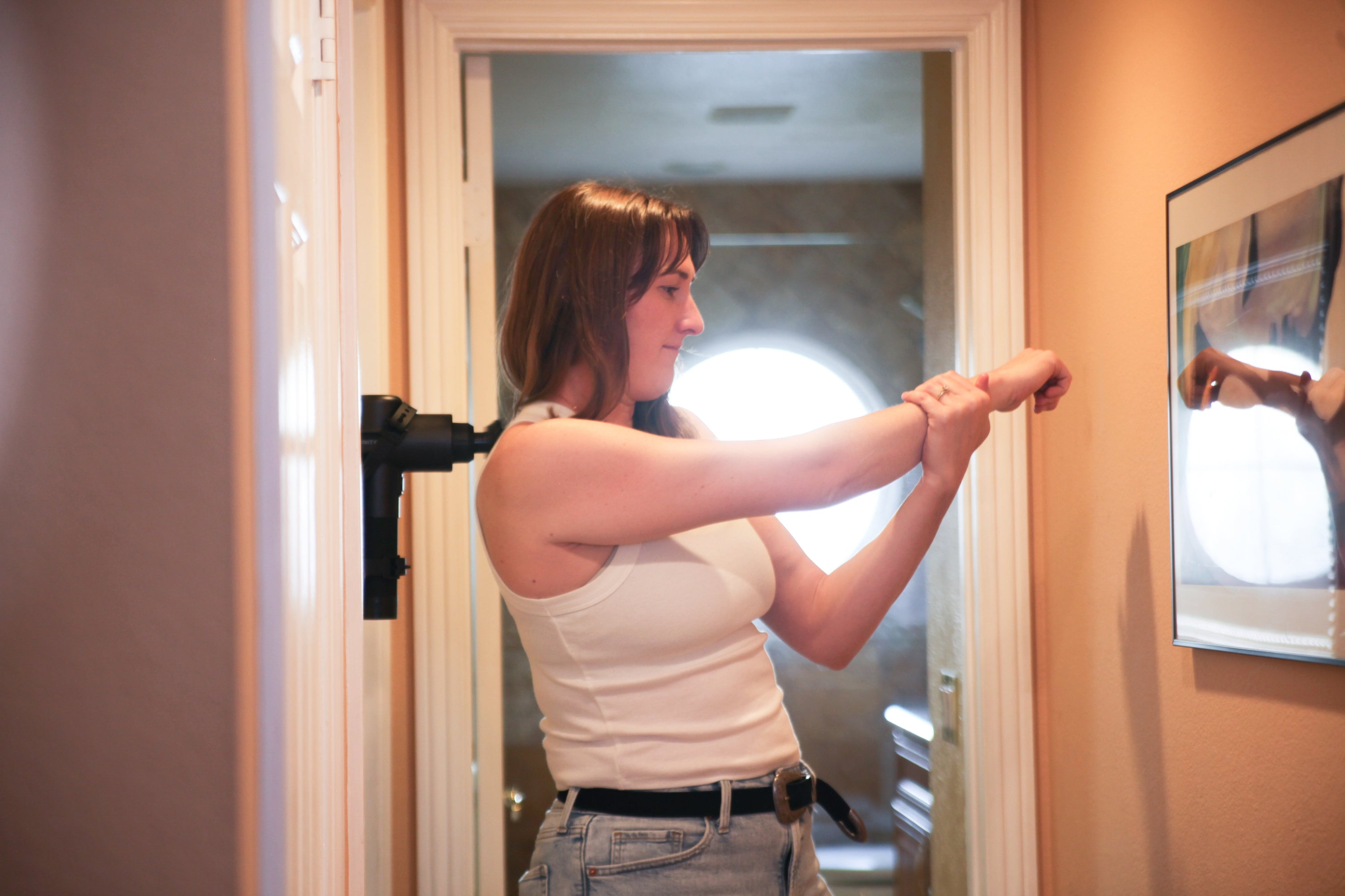 woman using sozo and massage gun on rotator cuff muscle